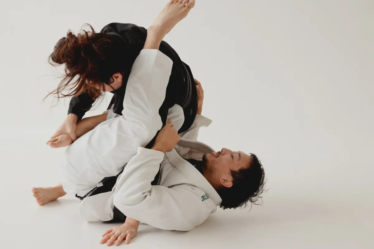 Two students in white and black gis practising a guard position.